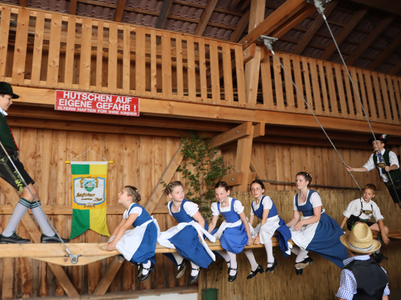 Kinder auf einer großen Schaukel in einem Holzstadel